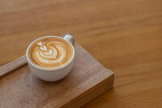 Hot coffee latte art on vintage wooden background
