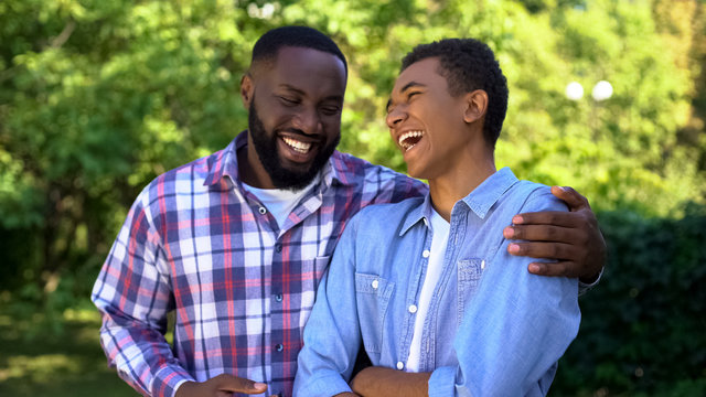 Young black man hugging younger brother laughing having fun together, family