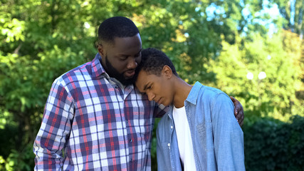 Kind father hugging teenage son admitting guilt, child upbringing, parenting