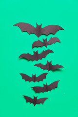 Halloween paper vampire bat decorations on a green background.