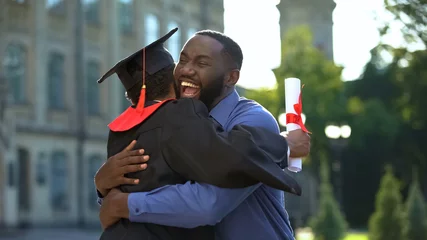 Cheerful father and graduating son hugging outdoor, study achievement, education © motortion