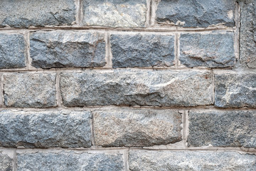 A wall of rough granite bricks with cement grout between them