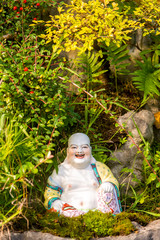 Smiling Buddha Hotey figurine in green grass