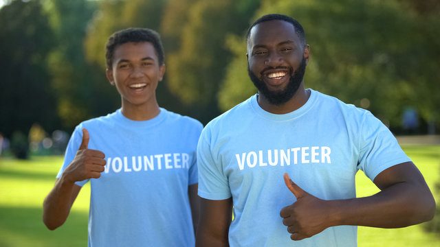 Positive afro-american males showing thumbs up, nature preservation volunteering