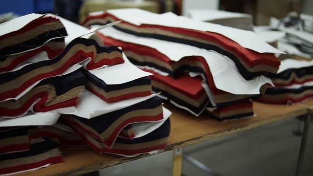 Set of layered fabric blanks . Fabrics overview on a table in a garment factory. Multi-colored fabrics for tailoring. A pile of fabrics for sewing clothes