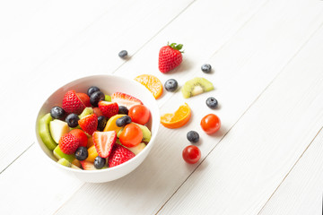 Healthy  food  concept  blueberries  kiwi strawberry tomato in  bowl  on  white wood background