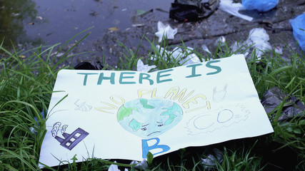 Painting with there is no planet phrase lying on polluted landfill in forest