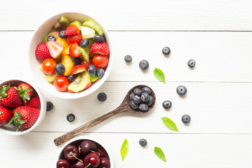Naklejka na ściany i meble Healthy food concept blueberries kiwi strawberry tomato on white wood background