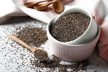 composition of Ceramic bowl with chia, wooden spoon and towels on wooden background, copy space