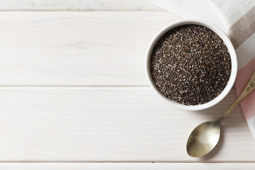 Bowl and spoons with chia on white background, close up