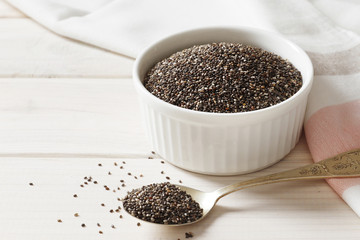 Bowl and spoons with chia on white background, close up