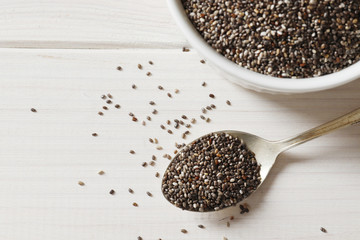 Bowl and spoons with chia on white background, close up