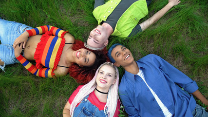 Joyful multiracial friends lying park grass together, youth freedom connection