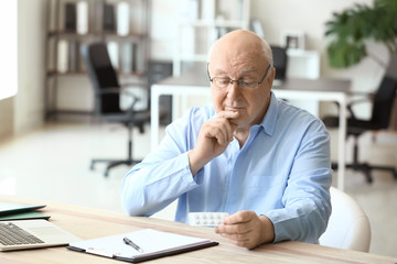 Elderly man taking medicine in office