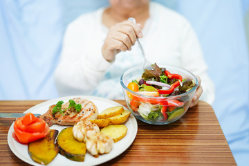 Asian senior or elderly old lady woman patient eating breakfast healthy food with hope and happy while sitting and hungry on bed in hospital..