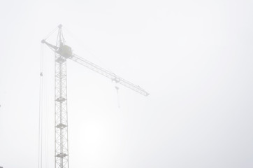 Construction crane in the fog.Calm haze morning at the construction site