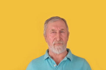 Handsome old bearded man with grey hair looking at camera over yellow background