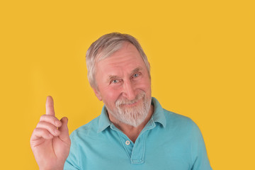 Elder man with beard and grey hair showed sign ides, gesturing with fingers over yellow background