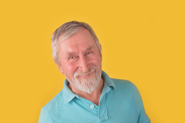 Handsome elder man with beard and grey hair tricky looking at camera over yellow background