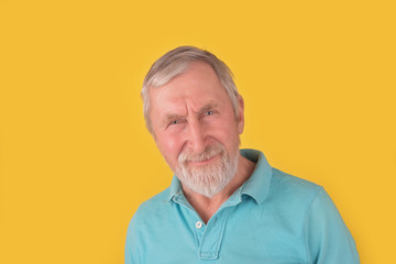 Obraz premium Handsome elderly bearded man with grey hair smiling and looking at camera over yellow background