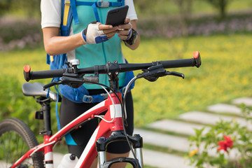 Fototapeta na wymiar Woman using smartphone while riding bike on sunny day in park