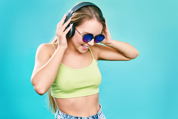 Pretty cool girl having fun and listens to music in the headphones on smartphone over colorful background.