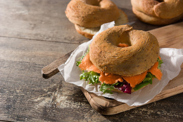 Bagel sandwich with cream cheese, smoked salmon and vegetables  on wooden table