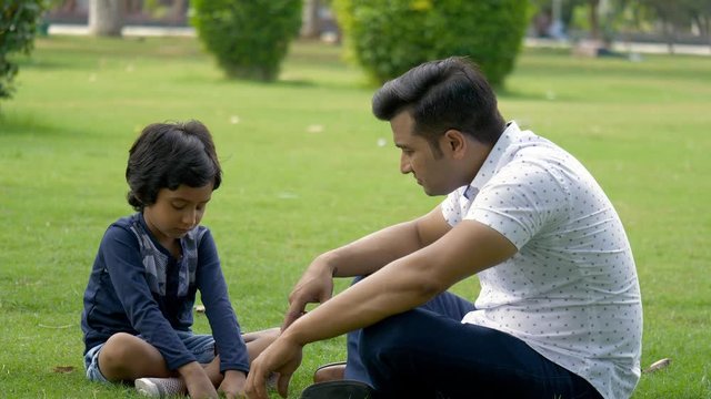 Angry Indian Father Scolding His Young Son For Plucking Grass - Save The Environment. Young Upset Dad Yelling At His Six-year-old Kid For Misbehaving In A Garden - Parenthood  Fatherhood Concept