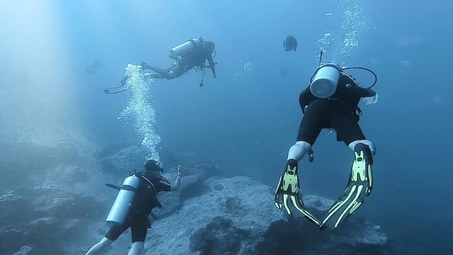 SCUBA diver dive buddy system in clear deep sea water with light rays