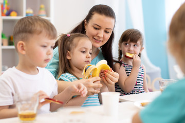 kindergarten teacher and preschoolers kids having break for fruits and vegetables - 297826750