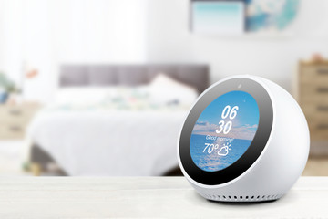 Personal assistant alarmclock and loudspeaker on a white wooden shelf of a smart home bedroom. Empty copy space for Editor's text.