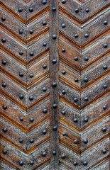 An old-style door made of old worn varnished panels riveted with button-head rivets as a background