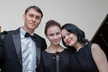 Musicians of the symphony orchestra. A young violinist and cellist play, the pianist accompanies them.