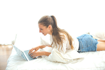 Happy woman at home using laptop sitting on bed, online working at home.Shopping online