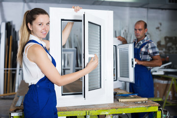 Fototapeta na wymiar Craftswoman in blue overalls demonstrating pvc window