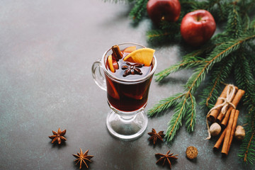 Christmas mulled wine or gluhwein with apple and orange slices in glass. Traditional drink on...