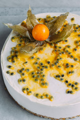 Passionfruit vegan cheesecake with Physalis on marble background with copy space