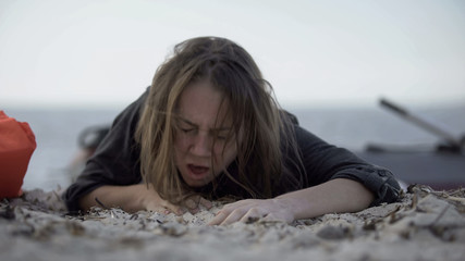 Woman coughing, trying to crawl on sand, surviving natural catastrophe, victim