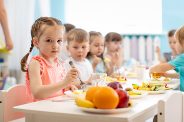 Kids have lunch in daycare. Children eat healthy food in kindergarten