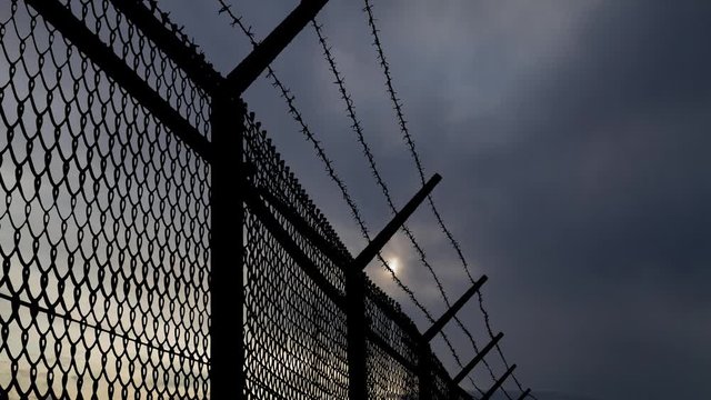 Border Wall with Mesh Steel and Barbed Wire, Time Lapse at Sunrise, Concept of Prison, Refugee, Isolation