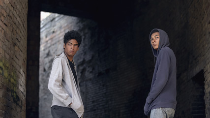 Obraz premium Two african teenagers in hoodie walking city together, dangerous city area