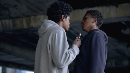 Angry african teenager threatening victim knife, young people cruelty, danger
