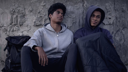 Black male teen supporting homeless friend sitting street, poverty threshold