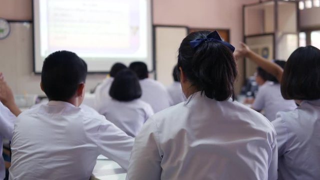 Asian classroom teaching of high school students in white uniform are actively studying science by raising their hands to answer questions that teachers ask them.