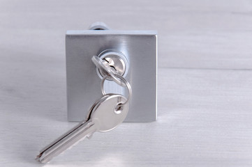 Lock core and door keys on a light background. Repair in the house. Installing a new lock on the door. Spare parts for the door on a gray wooden table.