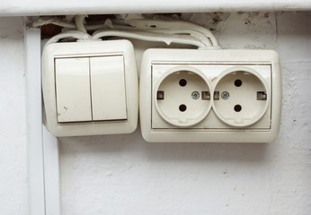 Old power socket and switch on the wall.