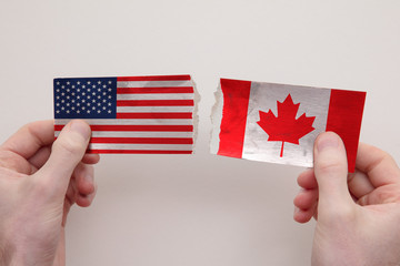 USA and Canada paper flags ripped apart. political relationship concept