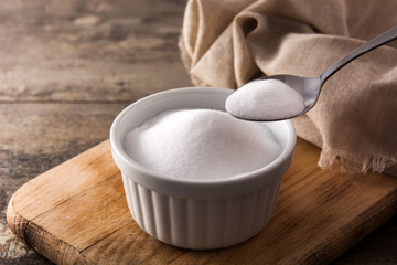 Baking soda in white bowl on wooden table. Copy space