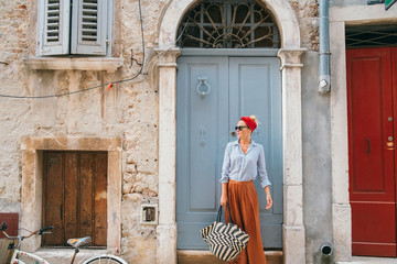 Portrait of beautiful stylish woman enjoying vacation in old Mediterranean town.