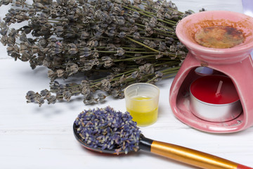 A bunch of lavender for aromatherapy and plant flowers in a spoon. Nearby is the aroma lamp. Oil is...